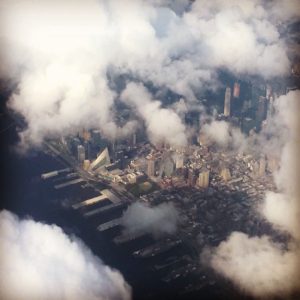 A glimpse of NYC from the air through the clouds. By Sharon McGukin